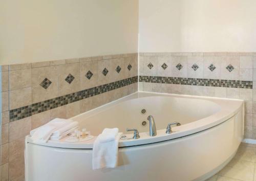 a white bath tub in a bathroom with tiles at Days Inn by Wyndham Minot in Minot