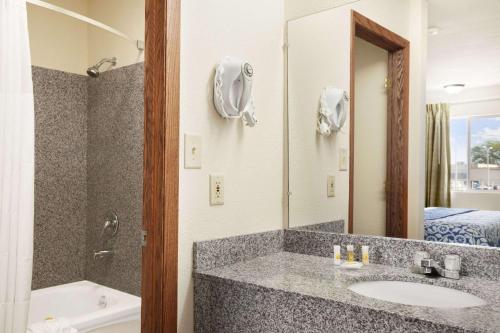 a bathroom with a sink and a tub and a mirror at Days Inn by Wyndham Champaign/Urbana in Champaign