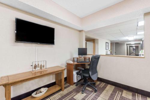 a hotel room with a desk and a television on a wall at Days Inn by Wyndham Bismarck in Bismarck