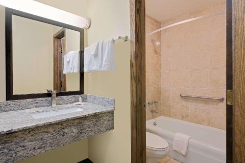 a bathroom with a sink and a tub and a toilet at Days Inn by Wyndham International Falls in International Falls