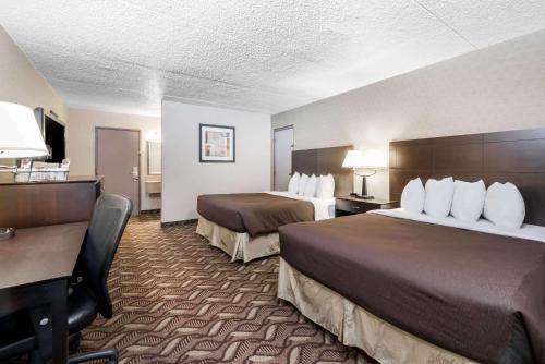 a hotel room with two beds and a desk at Days Inn by Wyndham Bismarck in Bismarck