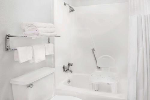 uma casa de banho branca com um WC e um chuveiro em Meridian Inn Hotel em Meridian