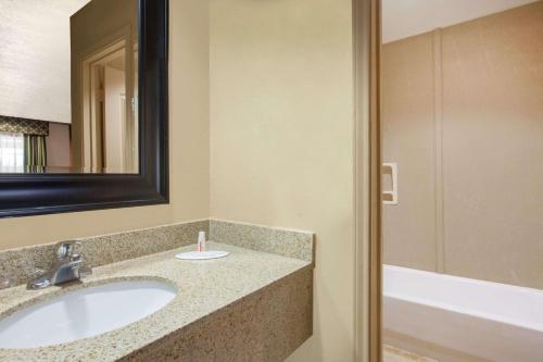 a bathroom with a sink and a mirror and a tub at Days Inn by Wyndham Centerville in Centerville