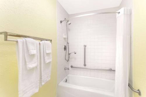 a bathroom with a tub and a shower with towels at Days Inn by Wyndham Savannah Airport in Savannah