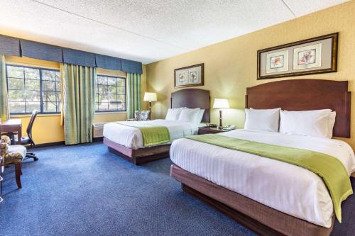 a hotel room with two beds and a chair at Days Hotel by Wyndham Mesa Near Phoenix in Mesa