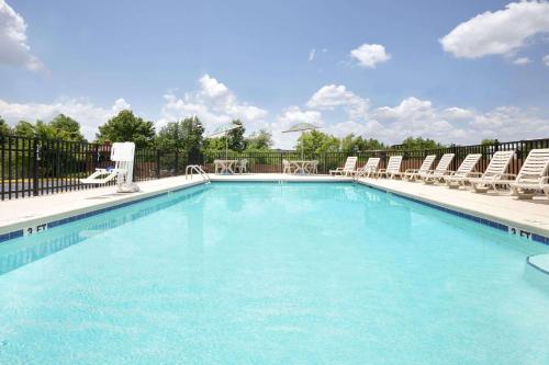 a large swimming pool with chairs and a table at Days Inn by Wyndham Columbus-North Fort Moore in Columbus