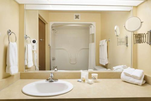 baño con lavabo y espejo grande en Days Inn by Wyndham Riviere-Du-Loup en Rivière-du-Loup