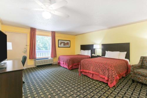 a hotel room with two beds and a television at Days Inn by Wyndham Savannah Airport in Savannah