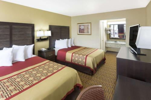 A bed or beds in a room at Days Inn by Wyndham Columbus-North Fort Moore