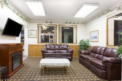 a living room with leather furniture and a tv at Days Inn by Wyndham Paxton in Paxton