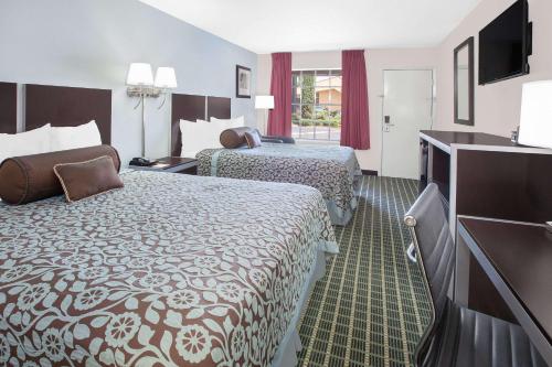 a hotel room with two beds and a flat screen tv at Days Inn by Wyndham Market Center Dallas Love Field in Dallas