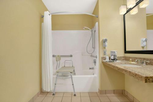 a bathroom with a shower and a chair next to a sink at Days Inn by Wyndham Globe in Globe