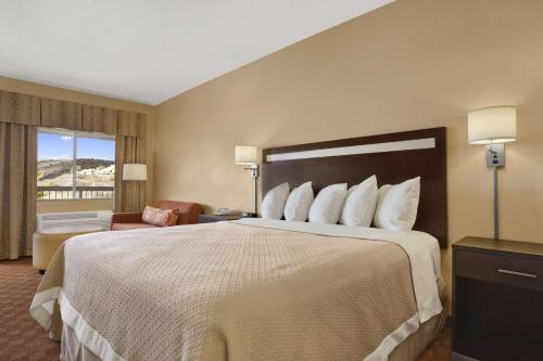 グローブにあるDays Inn by Wyndham Globeの大きなベッドと椅子が備わるホテルルームです。
