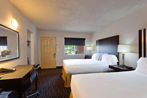 una camera d'albergo con due letti e una scrivania di Days Inn by Wyndham Chowchilla Gateway to Yosemite a Chowchilla