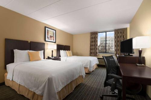 a hotel room with two beds and a desk at Days Hotel by Wyndham University Ave SE in Minneapolis