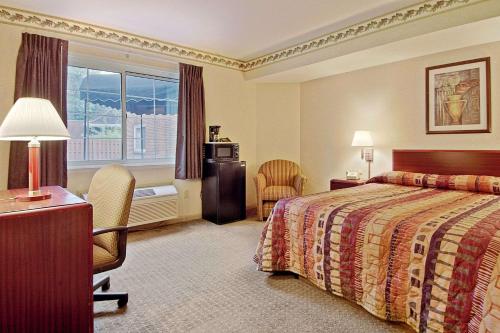 um quarto de hotel com uma cama, uma secretária e uma cadeira em Days Inn by Wyndham Cleveland Lakewood em Lakewood