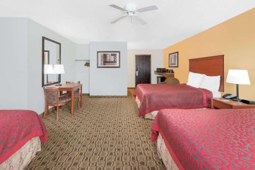 a hotel room with two beds and a desk at Days Inn by Wyndham Lamar in Lamar