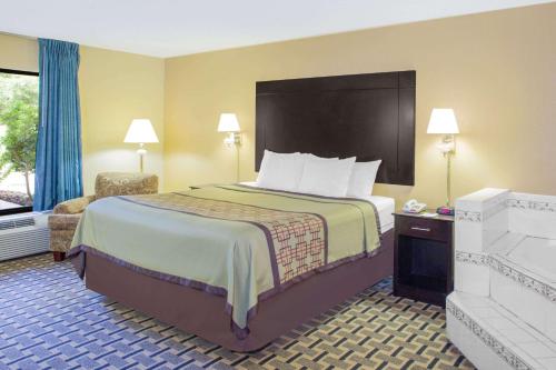a hotel room with a large bed and a chair at Days Inn by Wyndham Andalusia in Andalusia