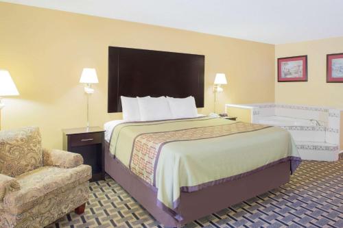 Days Inn by Wyndham Andalusia في أندلوسيا: غرفة فندقية بسرير كبير وكرسي