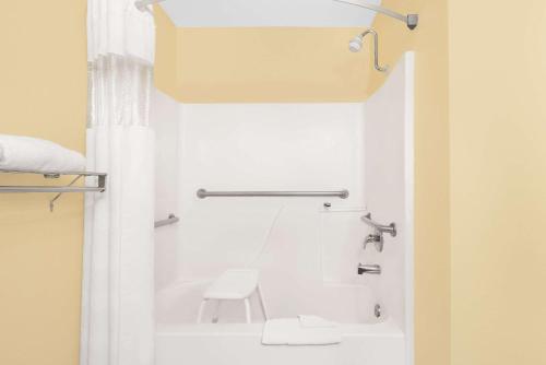 La salle de bains est pourvue d'une baignoire, de toilettes et d'une chaise. dans l'établissement Days Inn by Wyndham Lamar, à Lamar