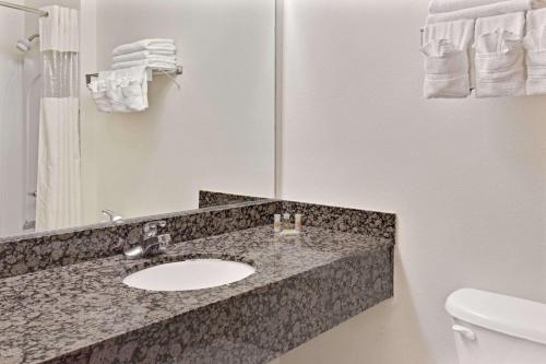 a bathroom with a sink and a toilet and a mirror at Days Inn & Suites by Wyndham Laurel Near Fort Meade in Laurel