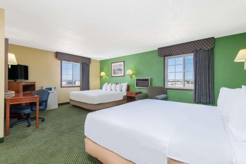 a hotel room with a large white bed and a desk at Days Inn by Wyndham Great Bend in Great Bend