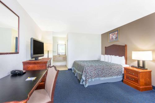 a hotel room with a bed and a desk and a television at Days Inn by Wyndham Arlington Pentagon in Arlington