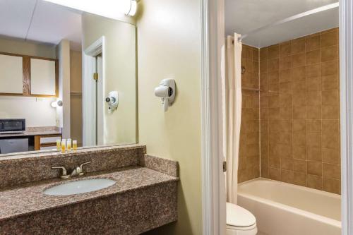 La salle de bains est pourvue d'un lavabo, de toilettes et d'une baignoire. dans l'établissement Days Inn by Wyndham Virginia Beach At The Beach, à Virginia Beach