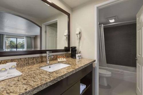 a bathroom with a sink and a toilet and a mirror at Days Inn by Wyndham Downey in Downey