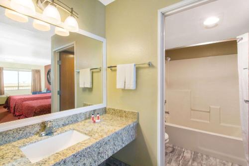 baño con lavabo, espejo y cama en Days Inn by Wyndham Buckeye, en Buckeye