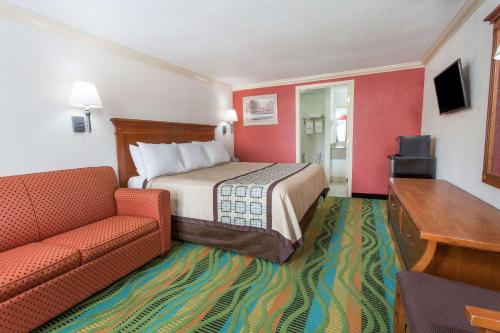 Habitación de hotel con cama y sofá en Days Inn by Wyndham Virginia Beach Town Center, en Virginia Beach