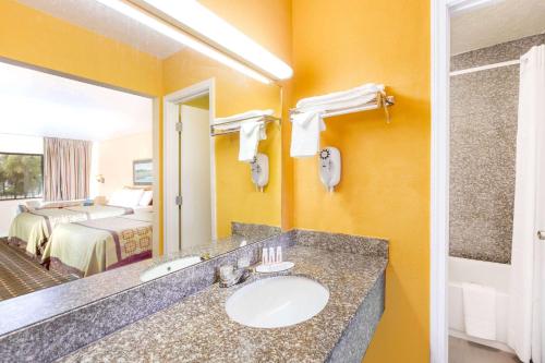 baño con lavabo, cama y espejo en Days Inn by Wyndham Little River, en Little River