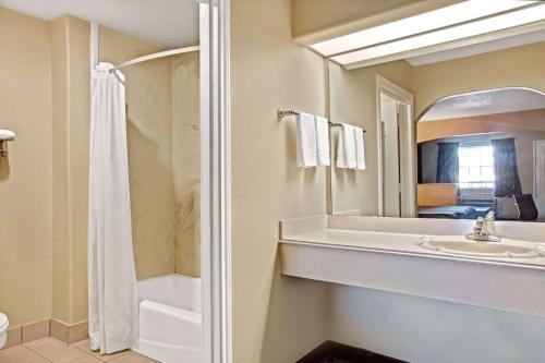 a bathroom with a sink and a shower and a mirror at Days Inn & Suites by Wyndham Houston North - Spring in Westfield