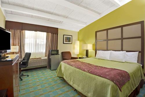 a hotel room with a bed and a flat screen tv at Days Inn by Wyndham Southington in Southington