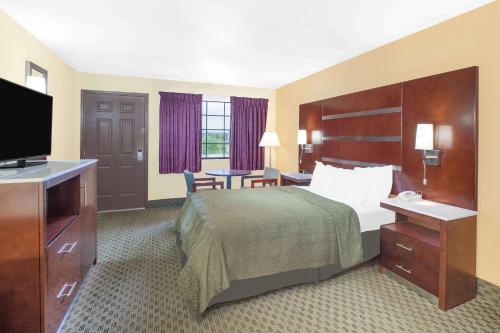 a hotel room with a bed and a flat screen tv at Days Inn by Wyndham Fayetteville in Fayetteville