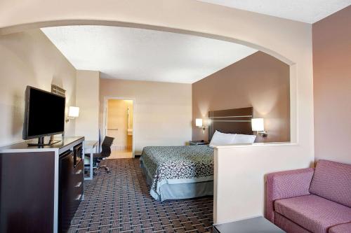 Days Inn & Suites by Wyndham Houston North - Spring في Westfield: غرفة فندقية بسرير وتلفزيون بشاشة مسطحة