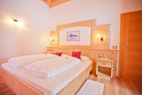 a bedroom with a large white bed with a wooden headboard at Apartaments Galina in Selva di Val Gardena