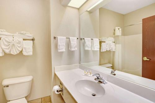 a bathroom with a sink and a toilet and a mirror at Days Inn & Suites by Wyndham Louisville SW in Louisville