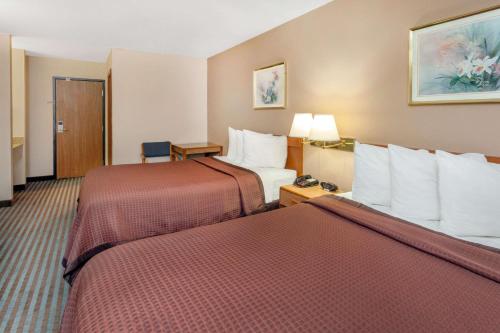 a hotel room with two beds with red sheets at Days Inn by Wyndham Charleston in Charleston