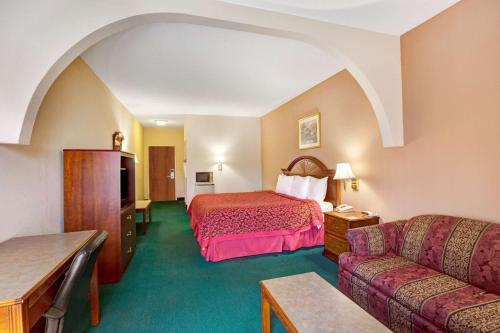 ルイスビルにあるDays Inn & Suites by Wyndham Louisville SWのベッドとソファ付きのホテルルーム