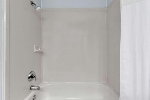 a white bathroom with a tub and a shower at Days Inn & Suites by Wyndham Dallas in Dallas