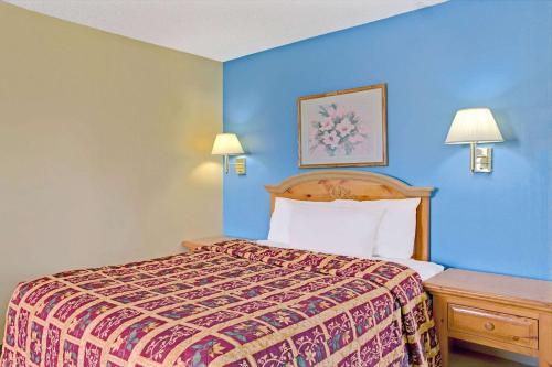 a hotel room with a bed and blue walls at Days Inn by Wyndham Lehi in Lehi