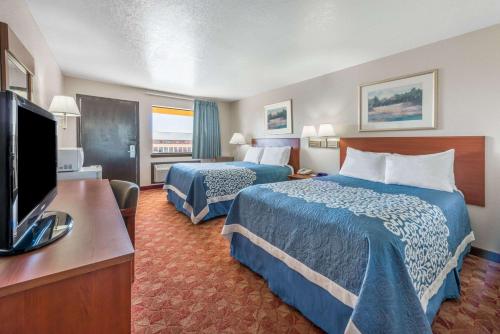 a hotel room with two beds and a flat screen tv at Days Inn by Wyndham Russell in Russell