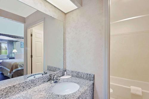 a bathroom with a sink and a mirror and a bed at Your Place Inn in Millington