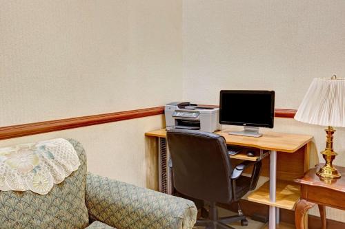 a room with a desk with a computer and a chair at Days Inn & Suites by Wyndham Louisville SW in Louisville