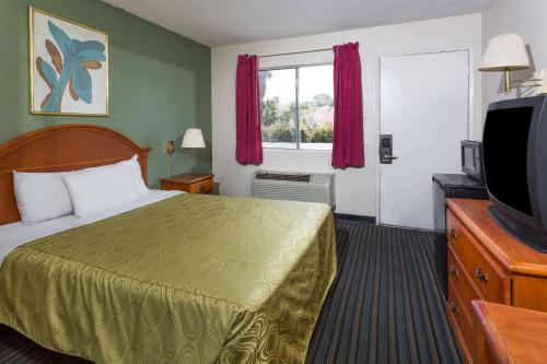 a hotel room with a bed and a television at Days Inn by Wyndham in San Bernardino in San Bernardino