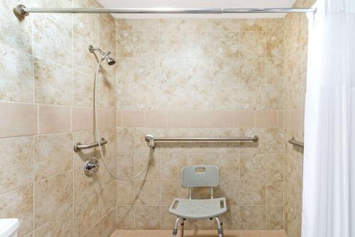 y baño con ducha y silla. en Days Inn by Wyndham Snyder, en Snyder