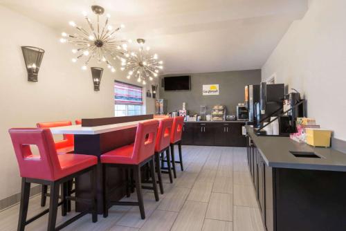a restaurant with a bar with red chairs at Hotel 1550 - SFO Airport West in San Bruno