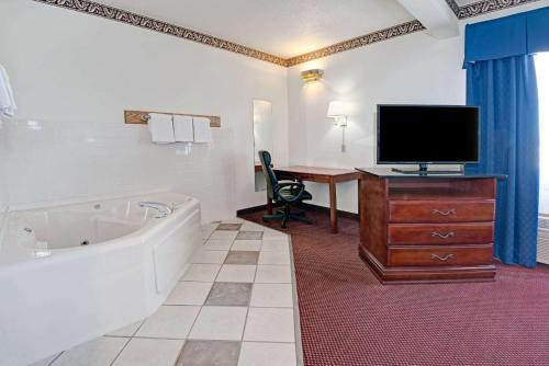 d'une salle de bains avec baignoire, d'un bureau et d'une télévision. dans l'établissement Days Inn by Wyndham Laramie, à Laramie