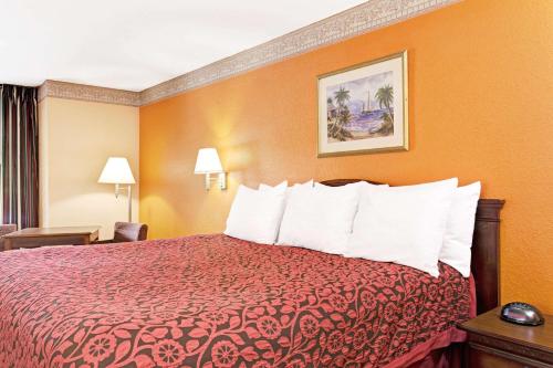 a hotel room with a bed with a red bedspread at Sunset Inn Daytona Beach in Daytona Beach
